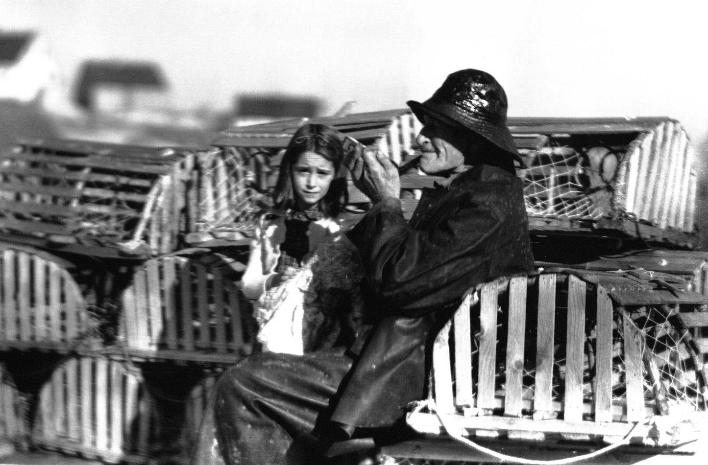 Albert Crooks in sou'wester sitting on lobster traps with a girl, Peggy's Cove, NS