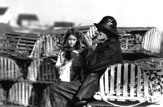 Albert Crooks in sou'wester sitting on lobster traps with a girl, Peggy's Cove, NS