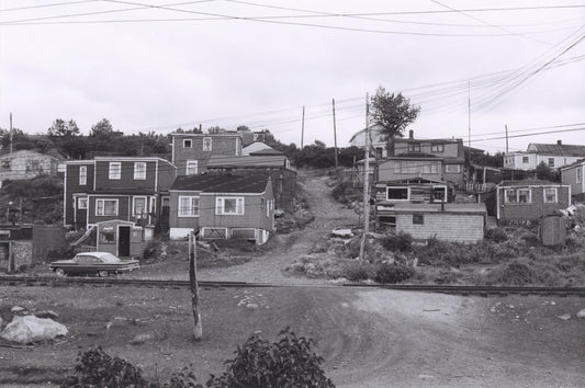 Africville houses on either side of a hillside lane, seen from the opposite side of the railroad tracks