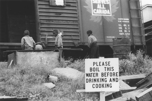 Boys beside Canadian National railcar, Africville, with "Please boil this water before drinking and cooking" sign